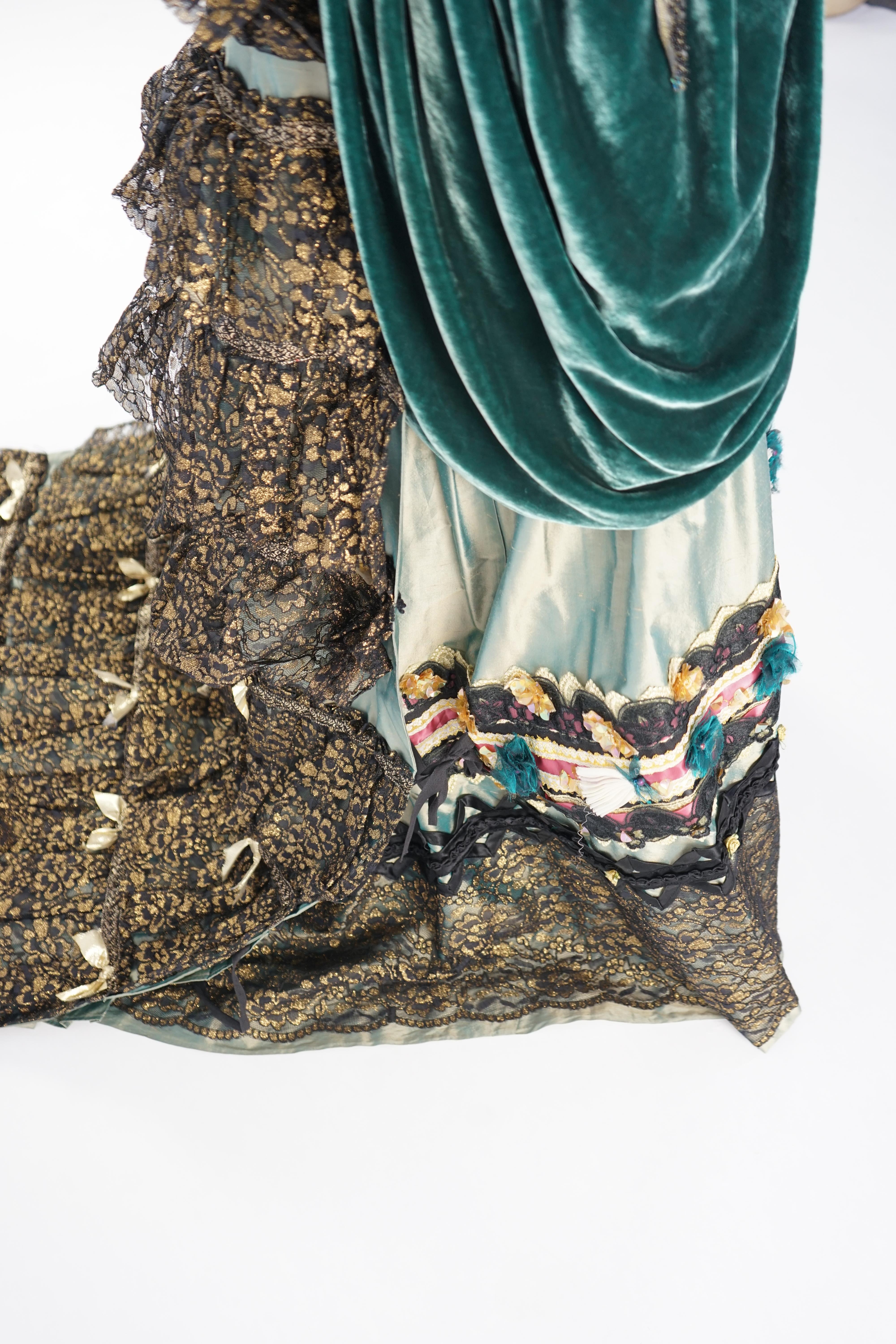 An Edwardian style lady's green taffeta skirt decorated with beaded, sequinned, ribboned border and swags of silk velvet, together with matching train layered with frilled black and gold lace, appliquéd with gold bows
